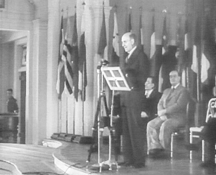 A man speaking at a lectern to rows of seated delegates in 1944.
