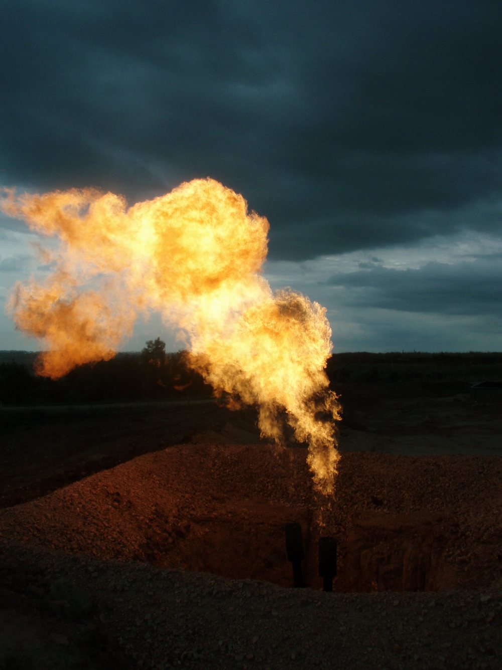 A gas flare burning against a night sky at an oil field.