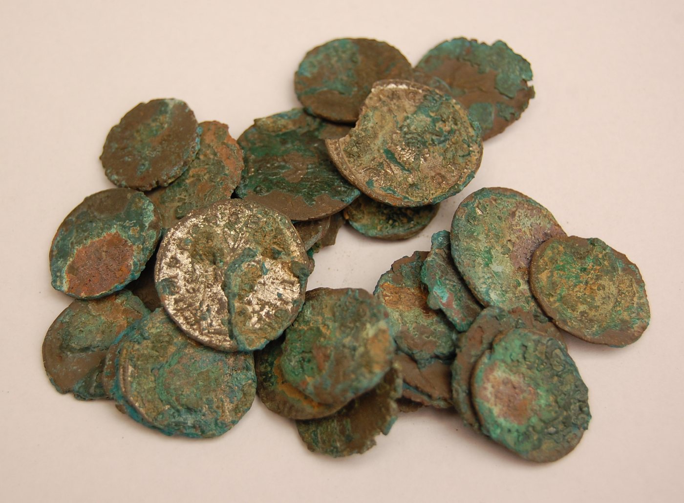 A pile of small corroded coins covered in green and brown crust.