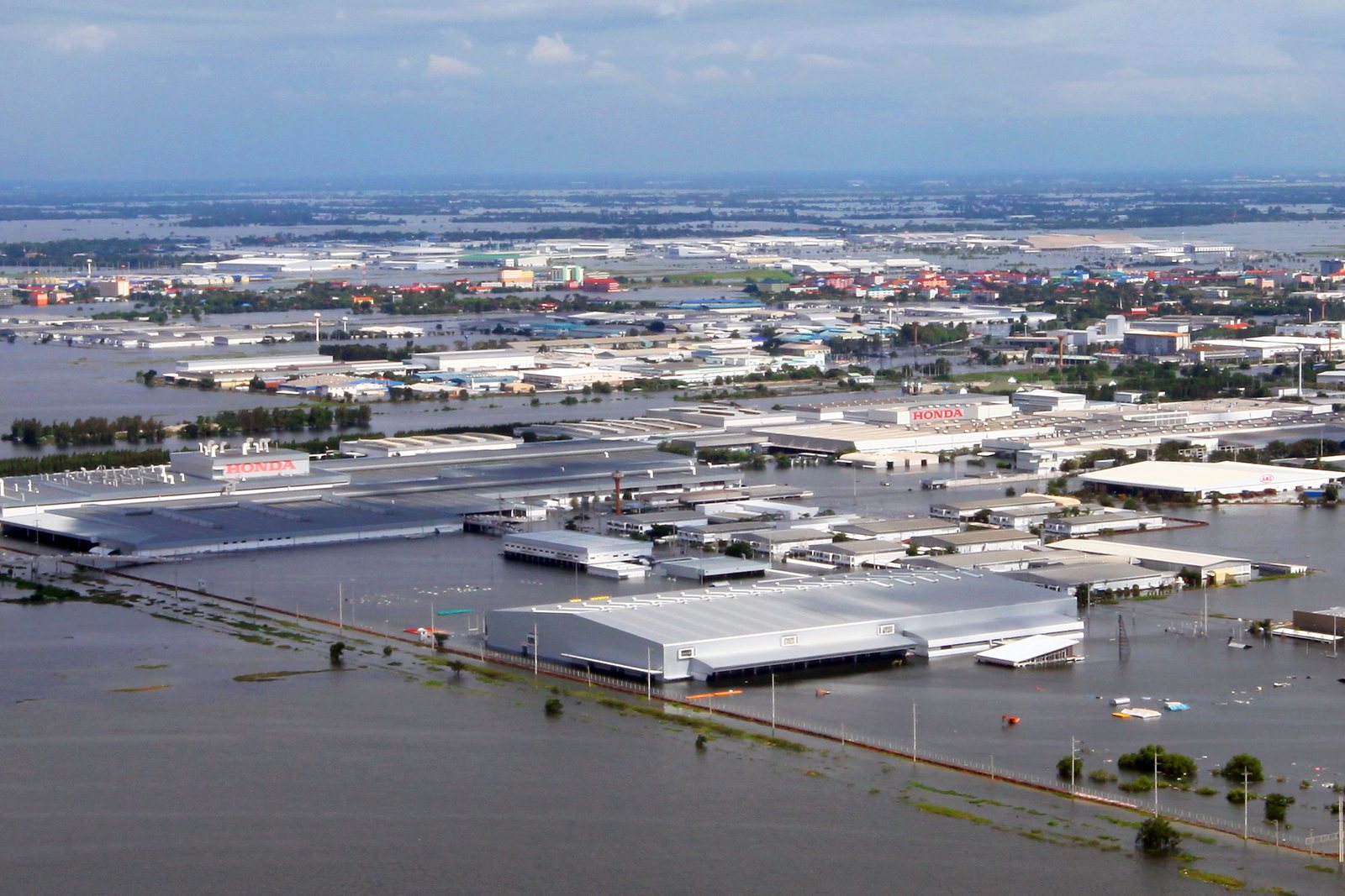 Aerial view of brown floodwater covering fields, roads and buildings north of Bangkok in October 2011