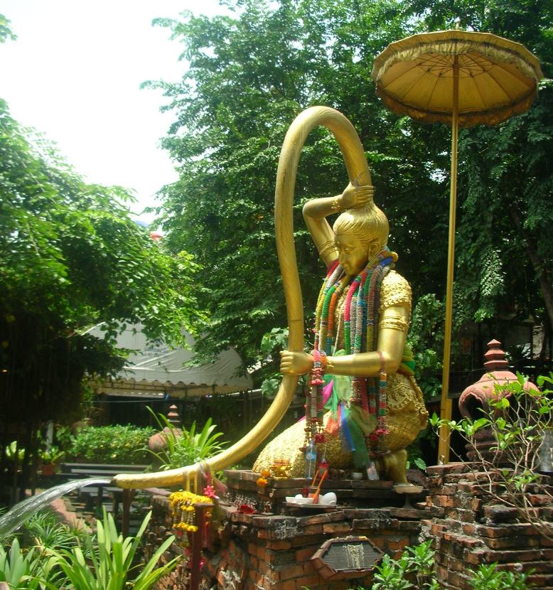 A gilded statue of Phra Mae Thorani, the Thai earth goddess, wringing water from her long hair.