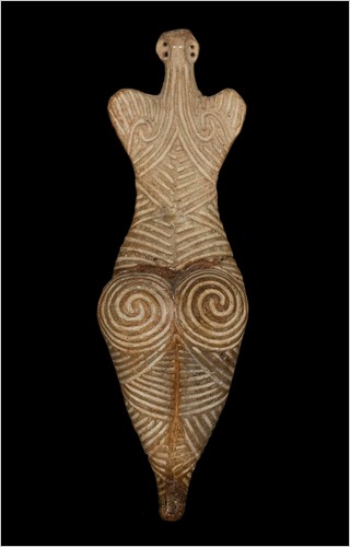 A Cucuteni-Trypillia clay figurine incised with dense spiral and linear patterns.