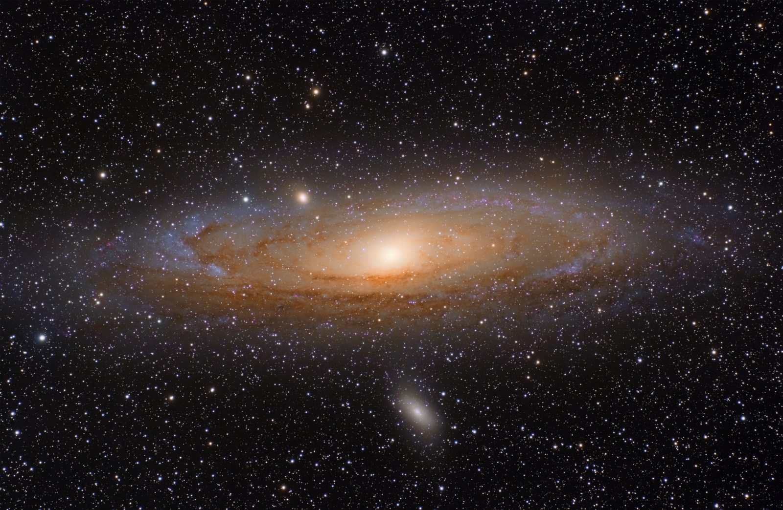 The Andromeda Galaxy, a bright oval of stars seen at an angle, with two small companion galaxies nearby